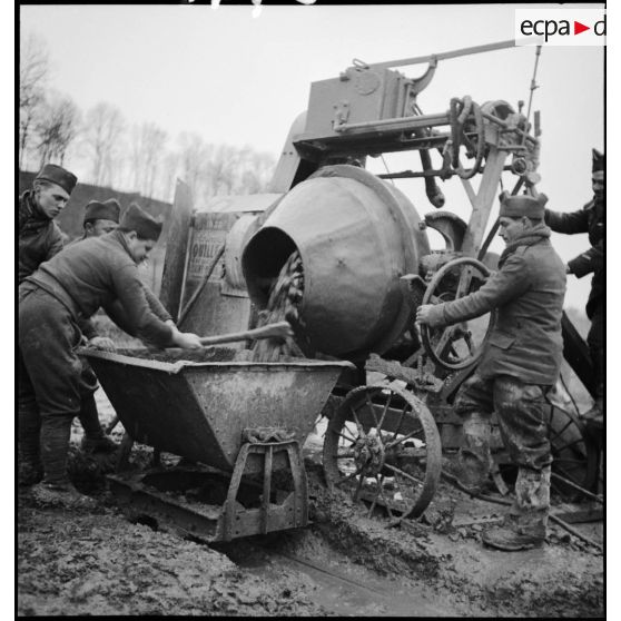 Des soldats (sapeurs ou pionniers) utilisent une bétonnière pour la construction d'un ouvrage fortifié de la ligne Maginot.