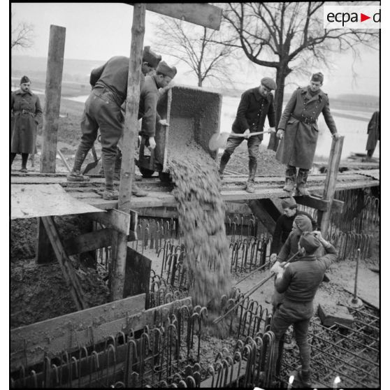 Des soldats (sapeurs ou pionniers) coulent le béton spécial pour la construction d'un ouvrage fortifié de la ligne Maginot.