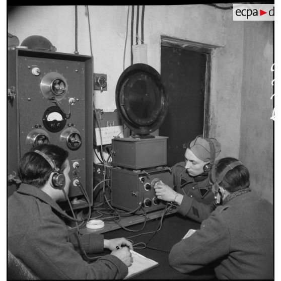 Des sapeurs radiotélégraphistes du 202e BGF (bataillon du génie de forteresse) suivent l'instruction d'un caporal du 8e RG (régiment du génie) sur un poste de radio dans la salle radio de l'ouvrage du Hackenberg de la ligne Maginot.