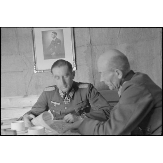 Dans un abri de campagne de la 205. Infanterie-Division, le commandant (Major) Hans Müller travaille en compagnie d'un autre officier.