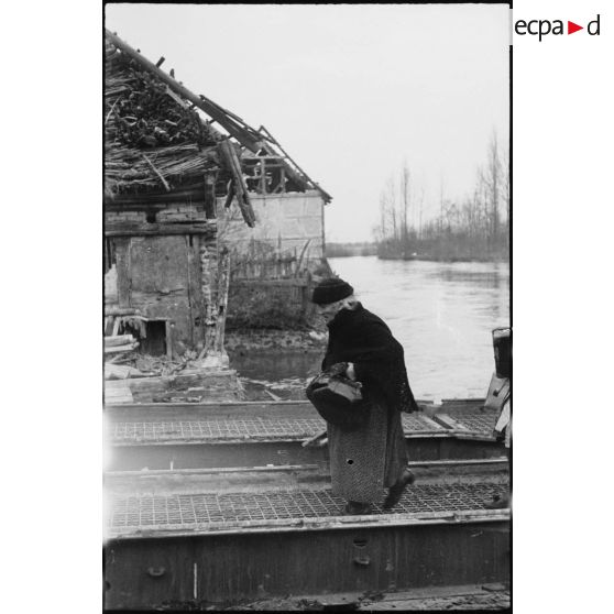 Les habitants évacués de Kogenheim regagnent leurs habitations en empruntant un pont flottant Treadway M2, mis en place par les sapeurs du 13e bataillon du génie (13e BG) de la 2e division blindée (2e DB).