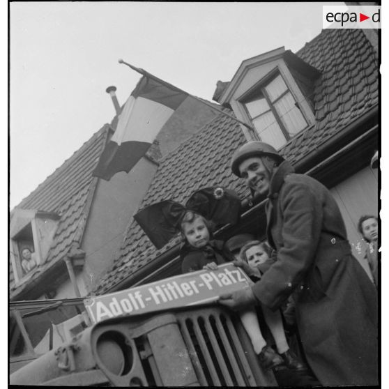 Soldat de la 1re DB et fillettes en costume traditionnel alsacien dans Mulhouse libérée.