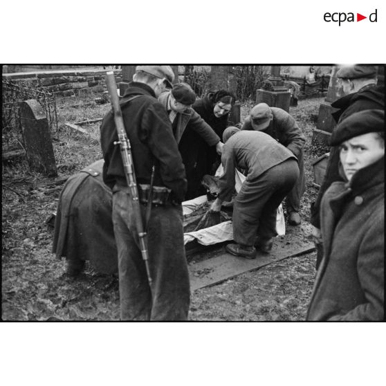 Dépose du corps d'un résistant fusillé dans un cercueil.