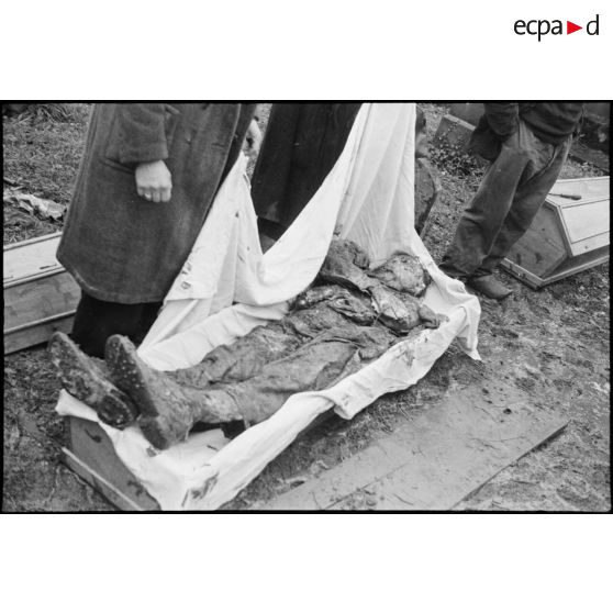 Dépose du corps d'un résistant fusillé dans un cercueil.