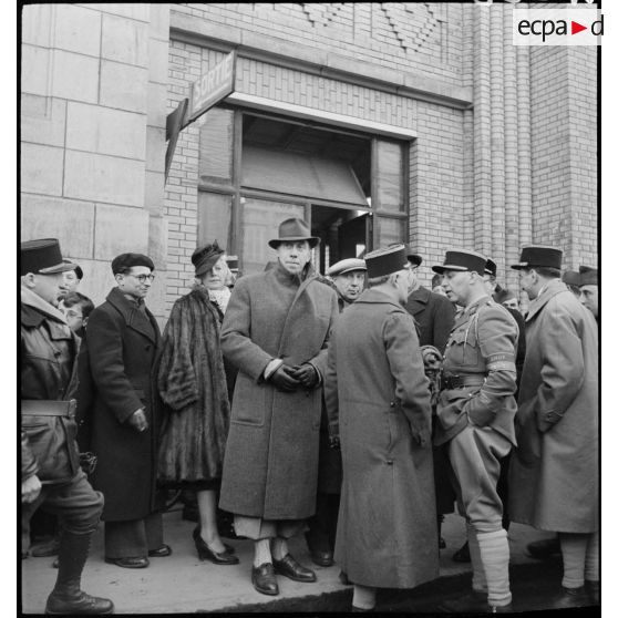 Les comédiens Blanche Denège, Fernandel et Andrex à la sortie d'une gare.
