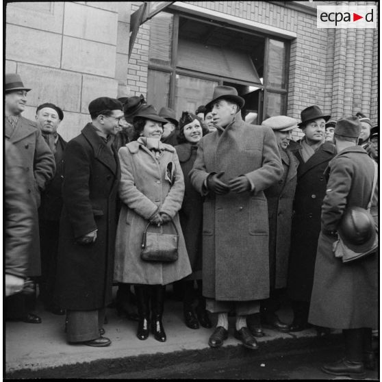 Les comédiens Blanche Denège, Fernandel et Andrex à la sortie d'une gare.
