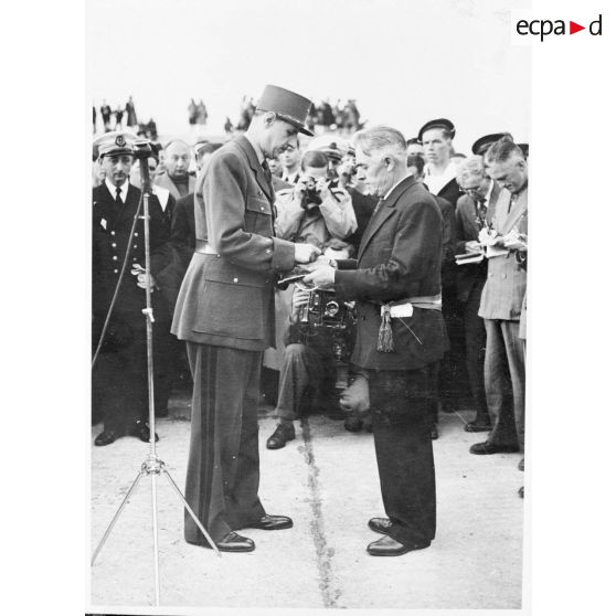 Au cours d'une cérémonie, le général de Gaulle remet la Croix de la Libération à Jean-Noël Marzin, maire de l'Ile de Sein. L'île a été nommée compagnon de l'ordre par décret du 1er janvier 1946.