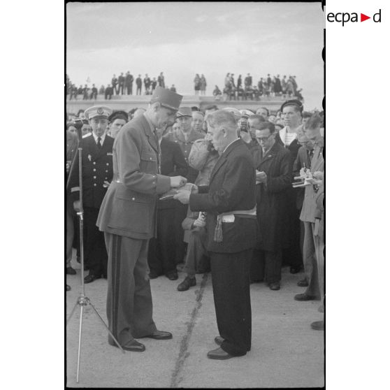 Au cours d'une cérémonie, le général de Gaulle remet la croix de la Libération à Jean-Noël Marzin, maire de l'Ile de Sein. L'île a été nommée compagnon de l'ordre par décret du 1er janvier 1946.