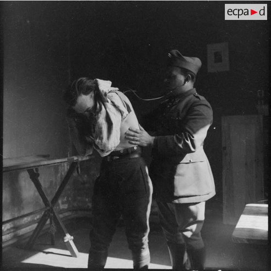 Un médecin militaire ausculte un soldat.
