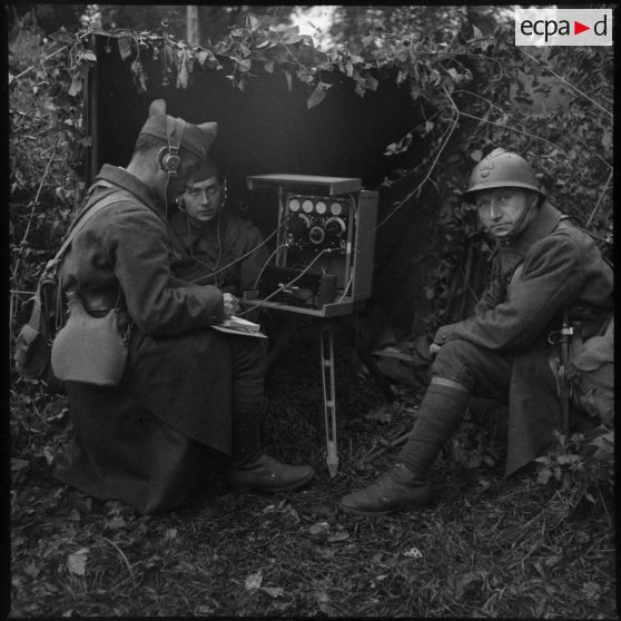 Deux soldats utilisent un poste radio sur le terrain.