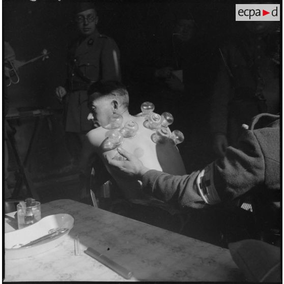 Un personnel médical pose des ventouses sur le dos d'un malade.