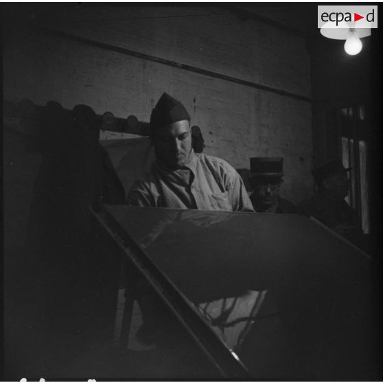 Plan américain d'un soldat français du service de santé à l'intérieur d'une pièce.