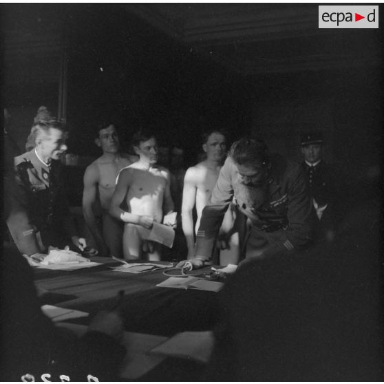 Des citoyens polonais nus passent devant des officiers français de la 1re armée pour le conseil de révision.