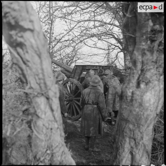 Vue partielle de trois quarts dos d'une pièce de 105 mm long modèle 1913 servie par des artilleurs du 142e RA.