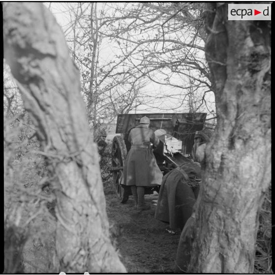 Vue partielle de trois quarts dos d'une pièce de 105 mm long modèle 1913 servie par des artilleurs du 142e RA.