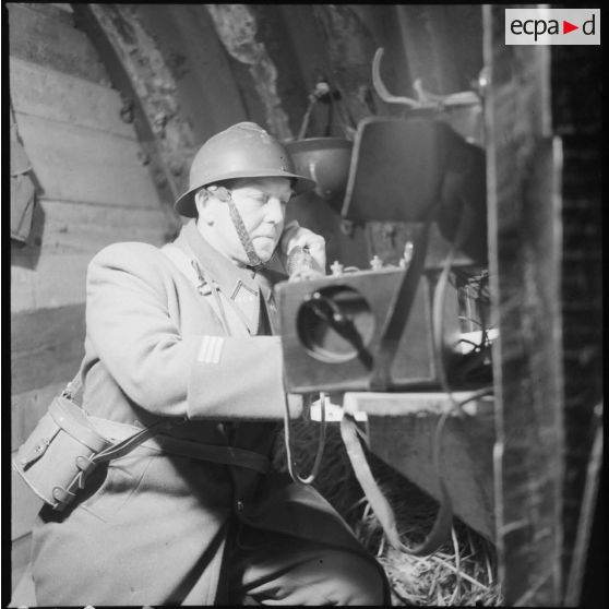 Portrait d'un capitaine du 404e RAAA qui utilise un téléphone de campagne à l'intérieur du poste de commandement.