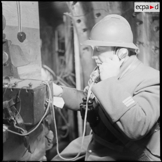 Portrait d'un capitaine du 404e RAAA qui utilise un téléphone de campagne à l'intérieur du poste de commandement.
