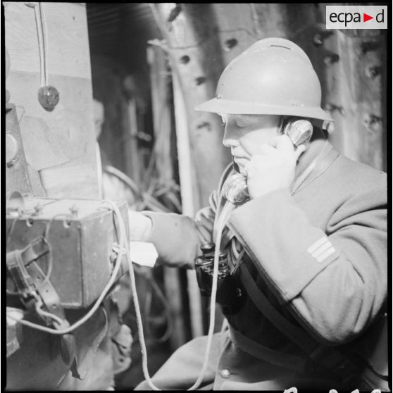 Portrait d'un capitaine du 404e RAAA qui utilise un téléphone de campagne à l'intérieur du poste de commandement.