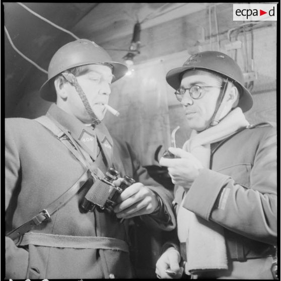 Portrait de groupe de deux officiers du 404e RAAA qui fument à l'intérieur du poste de commandement.