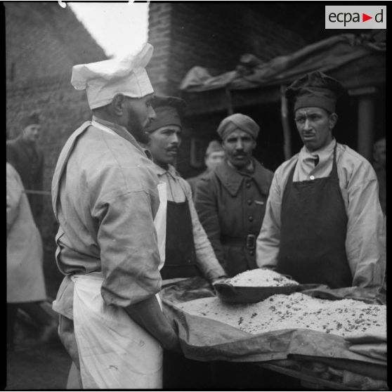 Photographie de groupe des cuisiniers du 4e RTM autour d'un plat de couscous préparé pour la fête.
