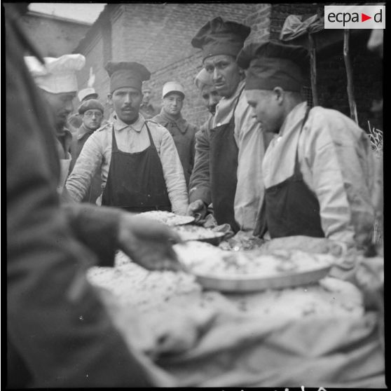 Photographie de groupe des cuisiniers du 4e RTM autour d'un plat de couscous préparé pour la fête.