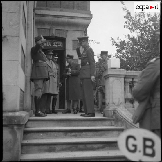Plan général d'officiers français et britanniques qui se saluent sur le porche d'une maison.