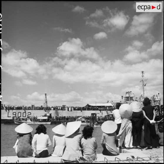 Sur le port, des Vietnamiennes observent l'embarquement de légionnaires quittant l'Indochine.