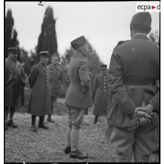 Le général d'armée Huntziger est photographié en pied alors qu'il discute avec des officiers qui l'entourent.