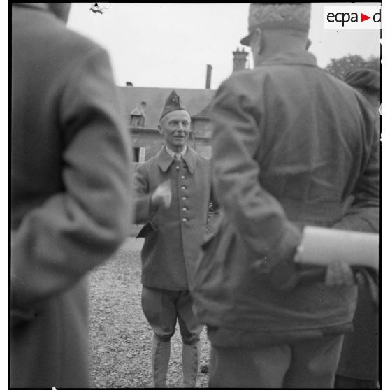 Le général d'armée Huntziger est photographié en pied alors qu'il discute avec des officiers qui l'entourent.