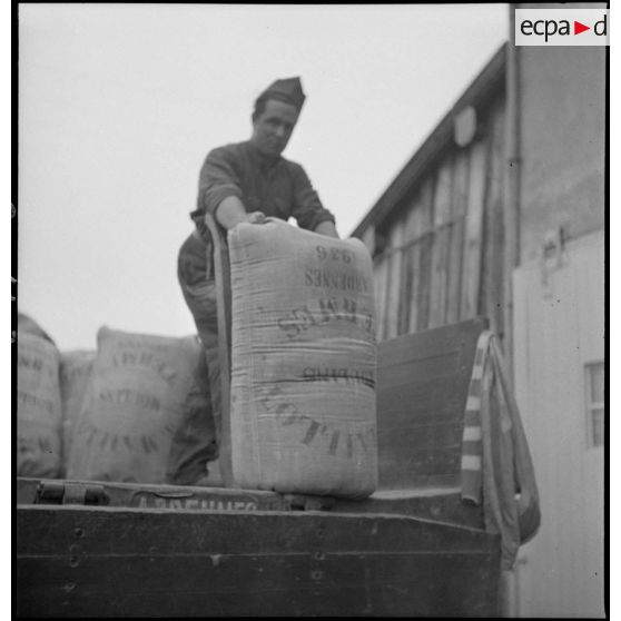 Des soldats de la 2e armée déchargent des sacs de farine d'un camion.