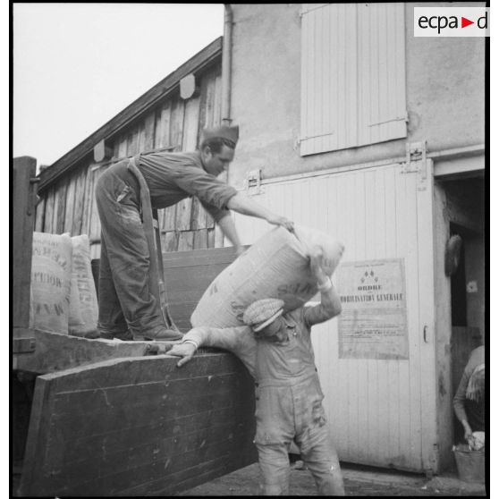 Des soldats de la 2e armée déchargent des sacs de farine d'un camion.