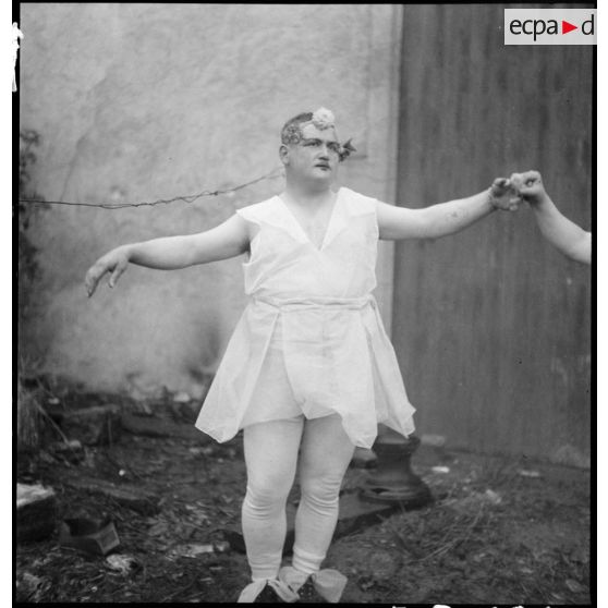 Un soldat travesti en danseuse pour les besoins d'une représentation théâtrale est photographié en pied.