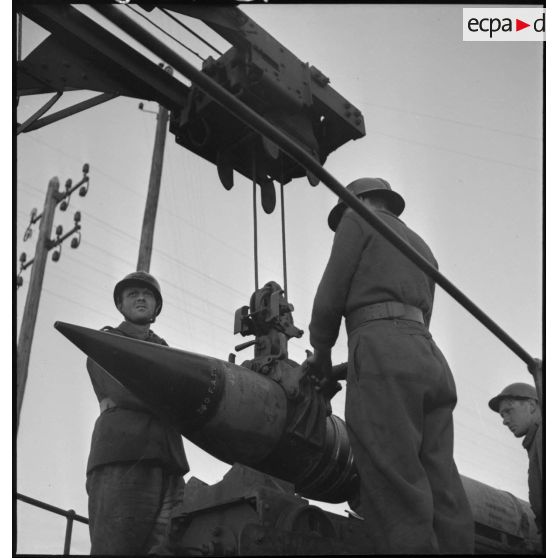 Deux artilleurs manipulent un obus grâce à la grue portique d'une pièce de 340 mm modèle 1912 de l'ALVF.