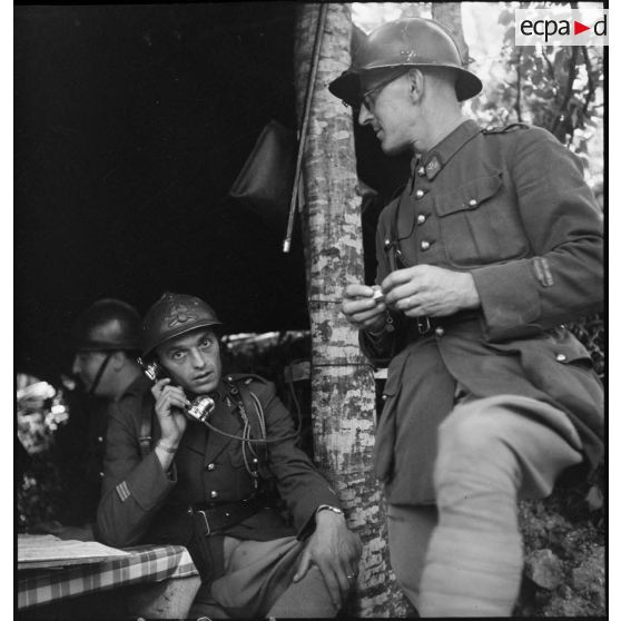 Photographie de groupe d'un lieutenant et d'un capitaine dans le PC d'une batterie du 24e RA dans la région de Montmédy.