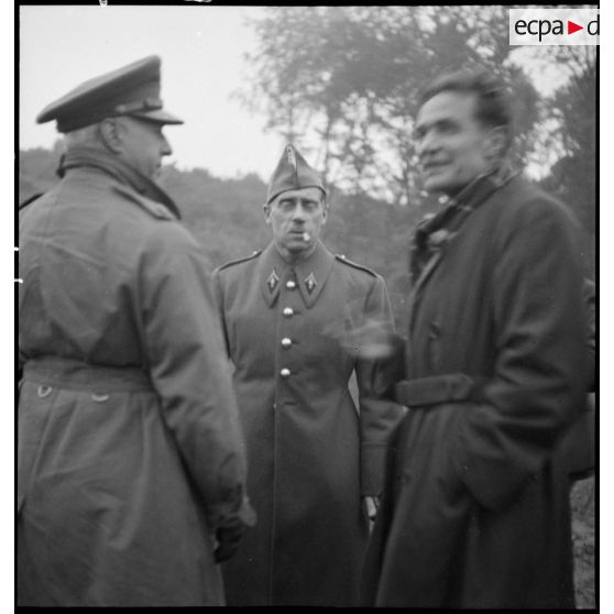 L'adjoint de l'attaché militaire des Etats-Unis discute avec un officier français et un journaliste.