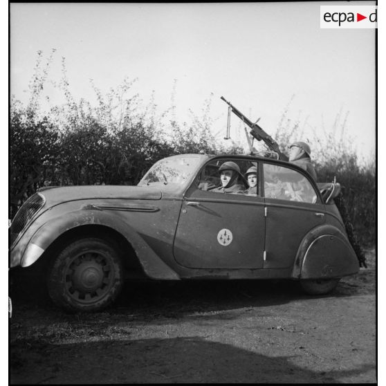 Plan général de profil d'un soldat du 3e escadron du 17e GRCA qui sert un FM M24/29 dans une Peugeot 202.