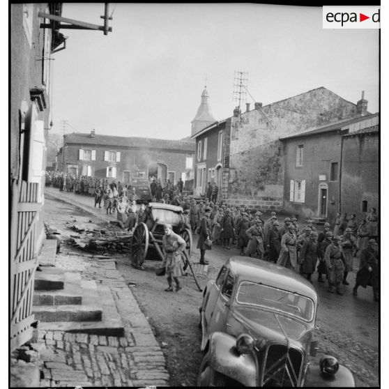 Plan général de permissionnaires de la 2e armée qui marchent dans la rue d'un village.