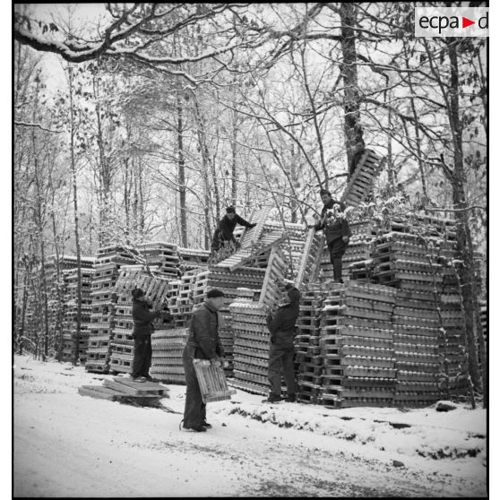 Plan général de soldats qui empilent des palettes de bois dans une forêt enneigée.