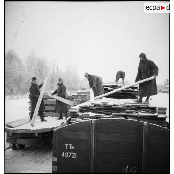 Des soldats de la 2e armée déchargent des planches de bois d'un wagon.