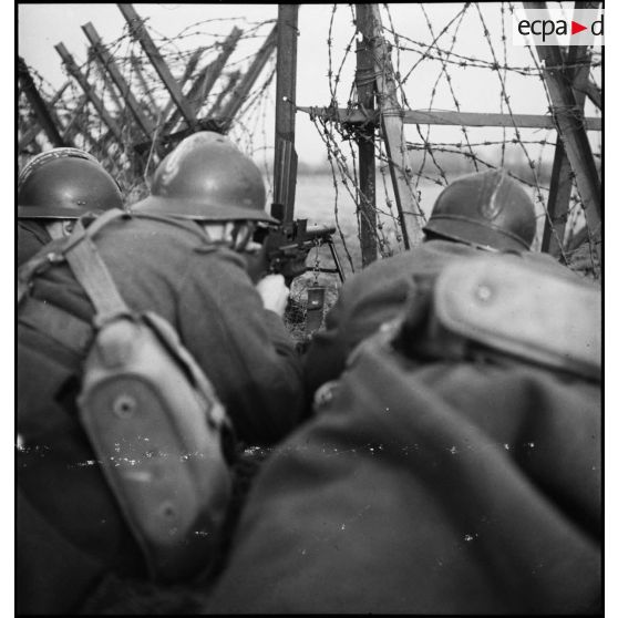 Un tireur de FM est posté derrière un réseau de barbelés lors d'une patrouille de la 2e armée près de Velosnes.