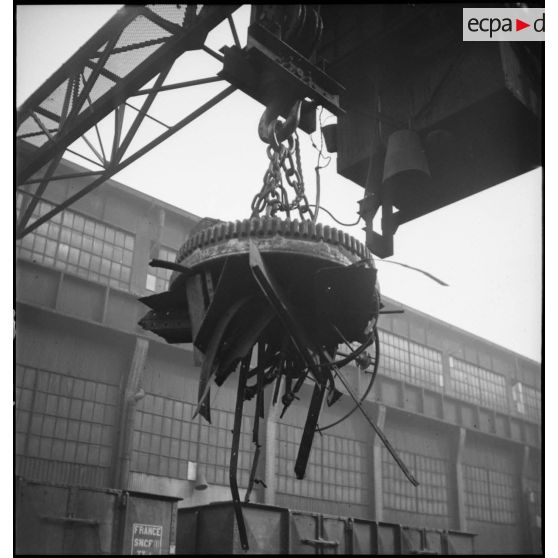 Plan moyen d'un aimant monté sur une grue portique à l'extérieur de l'usine du Creusot qui ramasse la ferraille.