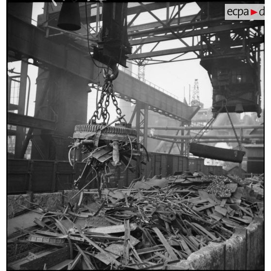 Plan moyen d'un aimant monté sur une grue portique à l'extérieur de l'usine du Creusot qui ramasse la ferraille.