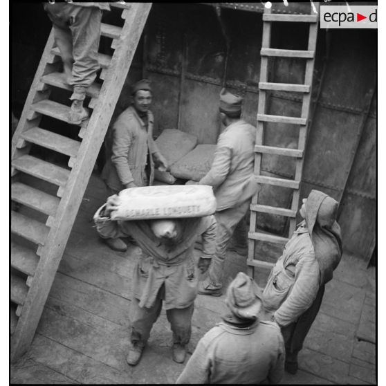 Des soldats de la 2e armée déchargent des sacs.