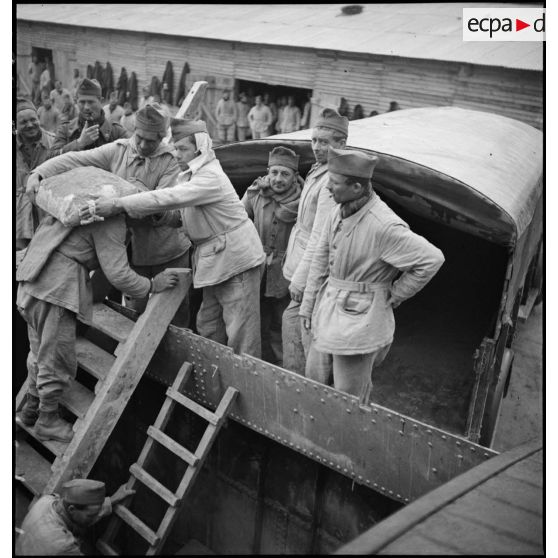 Des soldats de la 2e armée déchargent des sacs.