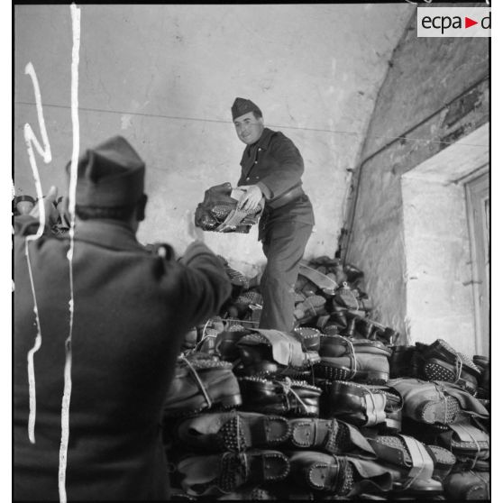 Des soldats manipulent des brodequins dans un magasin de l'intendance de la 2e armée.