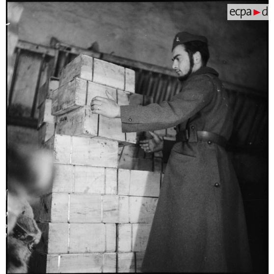 Un soldat manipule des caisses de bois dans le magasin d'un centre de l'intendance de la 2e armée.