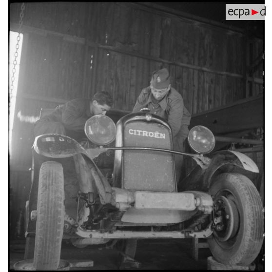 Deux mécaniciens travaillent sur un véhicule Citroën à l'atelier de réparation de campagne.
