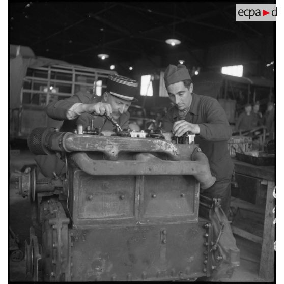 Un capitaine et un mécanicien travaillent sur un moteur dans l'atelier de réparation de campagne.
