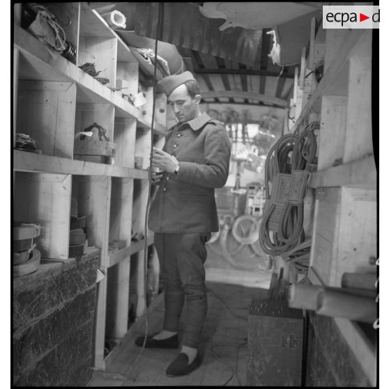 Un mécanicien cherche une pièce mécanique dans le magasin de l'atelier de réparation de campagne.