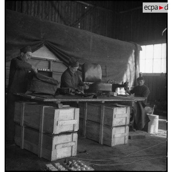 Dans l'atelier de réparation de campagne des soldats travaillent sur la sellerie de véhicule.